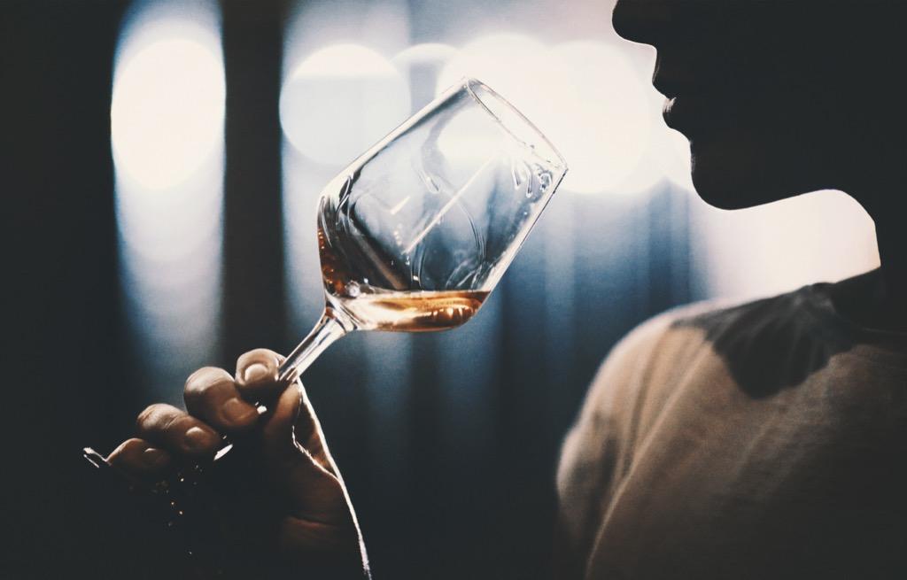 Person verkostet ein Glas Weißwein