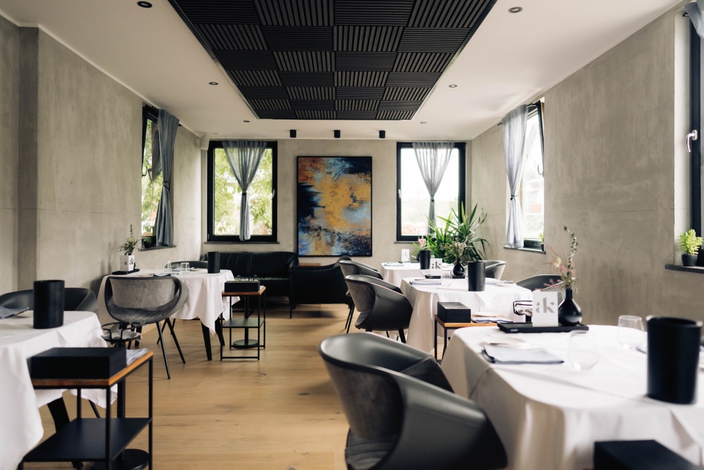 Heller Gastraum des Restaurants mit weiß eingedeckten Tischen und großem Wandbild