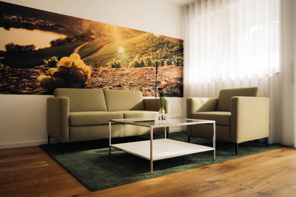 Wohnbereich mit Sofa, Sesseln und Weinberg-Wandbild