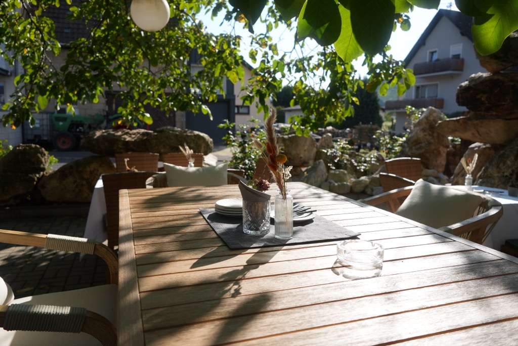Holztisch auf der Terrasse im Schatten der Walnussbäume